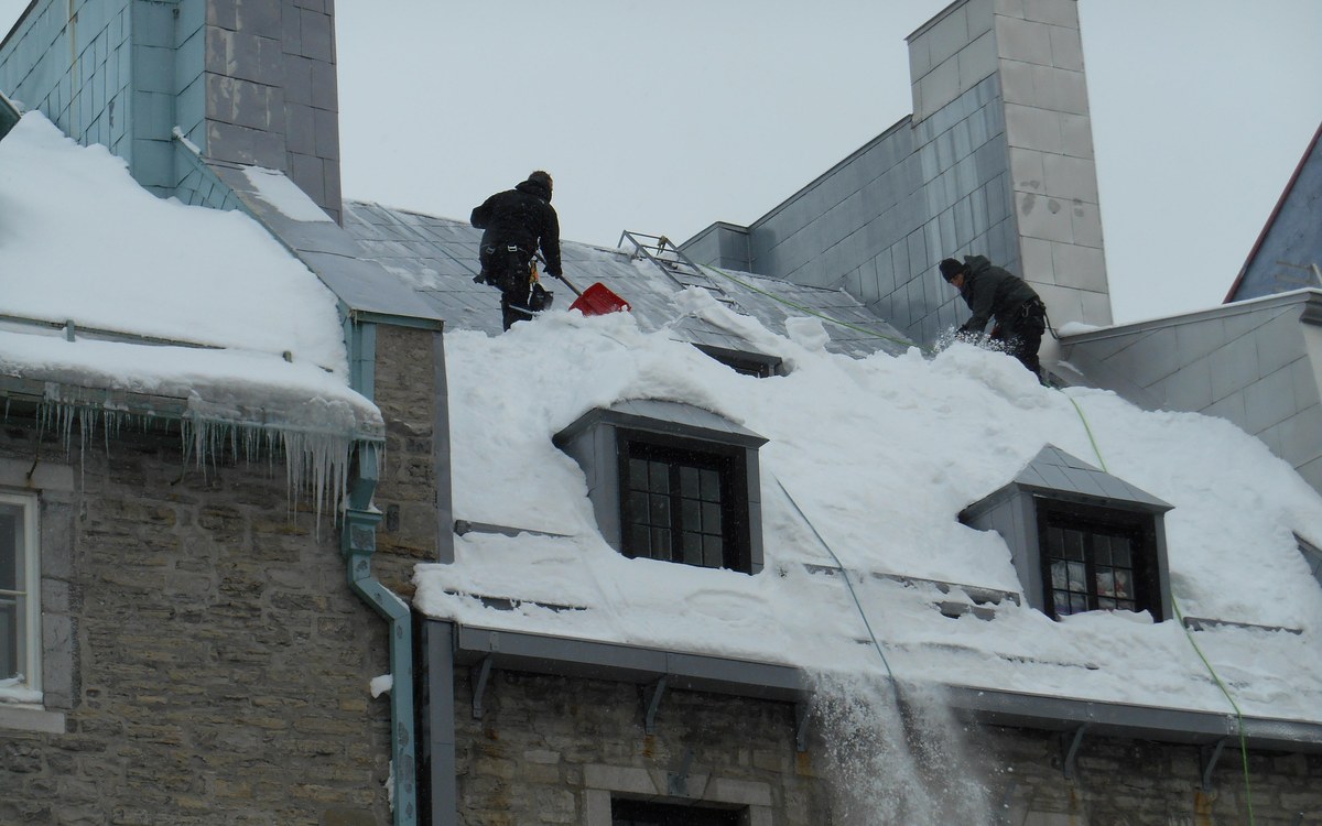Élimination manuelle de la glace sur corniche de toit