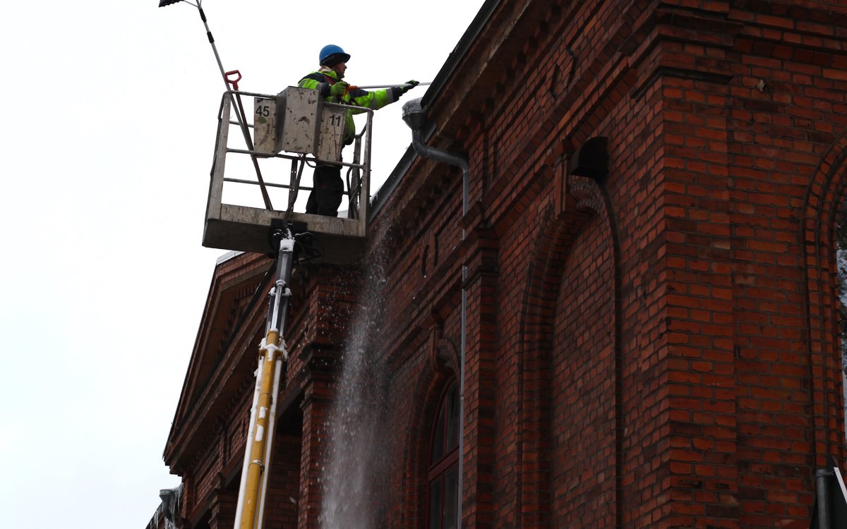 Techniciens de déneigement de toiture en nacelle sécurisée